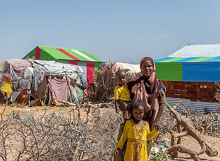 Somalierin und Kind vor improvisierten Behausungen