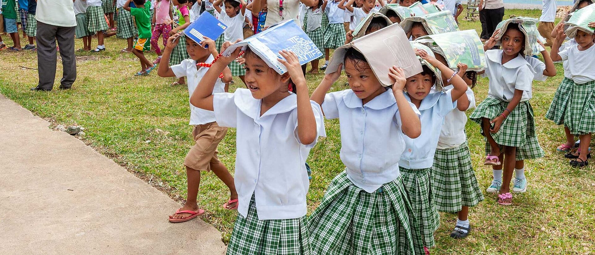 Children protecting their heads with books