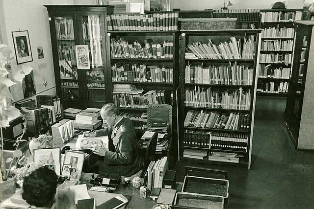 Mann in Raum mit Regalen voller Bücher