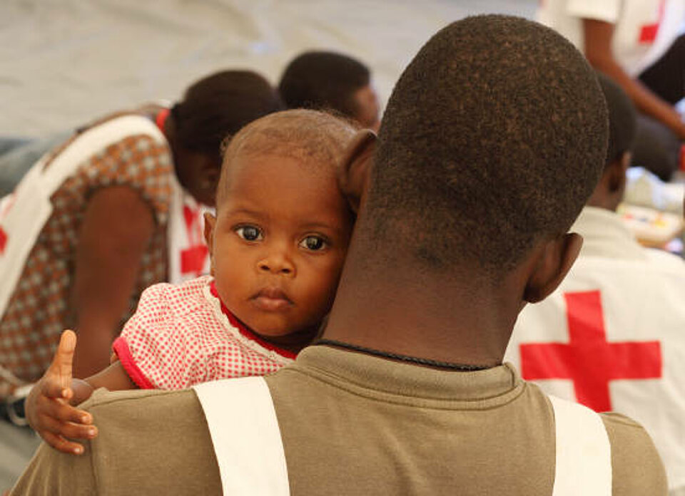Foto: Baby schaut über die Schulter von Sozialarbeiter Jerome in die Kamera