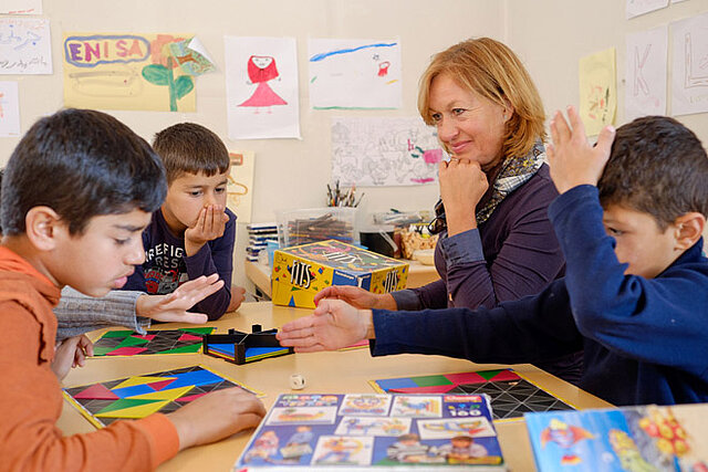 Drei Kinder und eine Betreuerin an einem Tisch