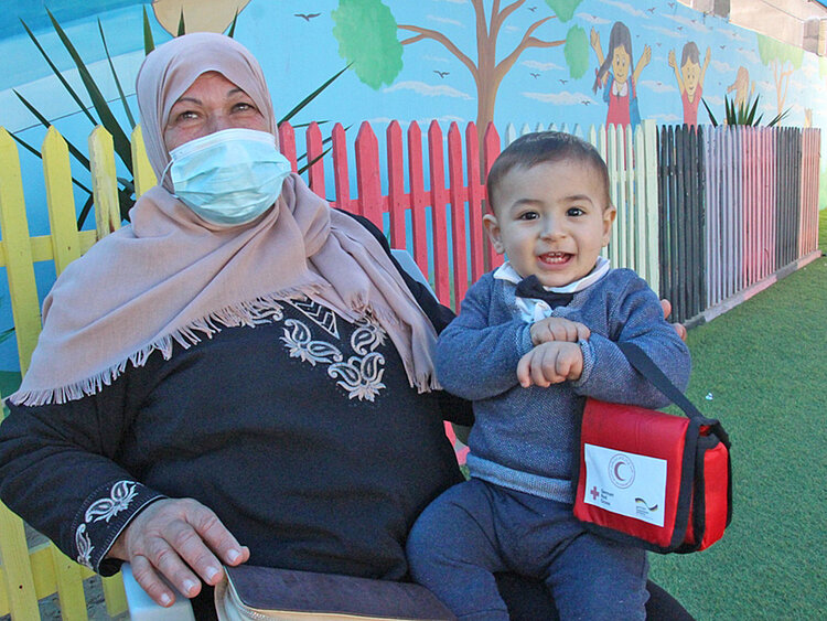Rothalbmond-Helfer und Mädchen in Palästina (Gazastreifen) mit Rotkreuz-Tasche 