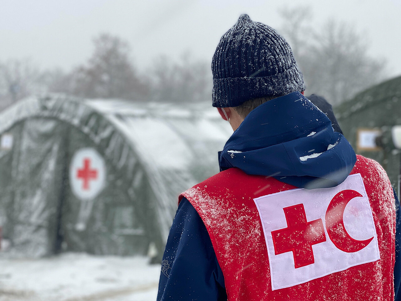 Rotkreuz-Helfer vor Zelt im Schnee