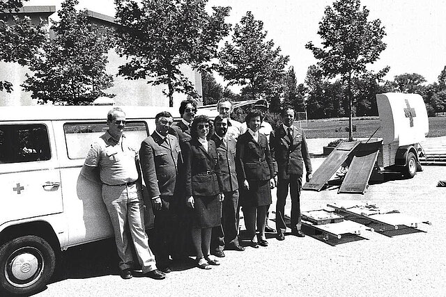 Menschengruppe vor Einsatzwagen mit Hänger