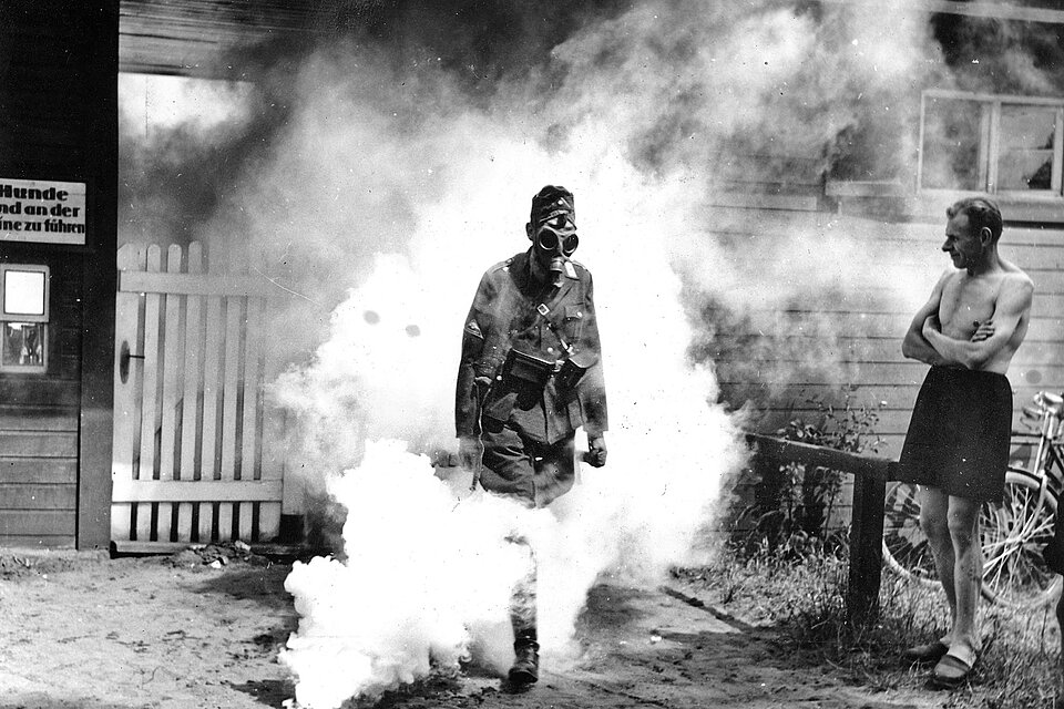 DRK-Helfer mit Gasmaske läuft durch Rauch