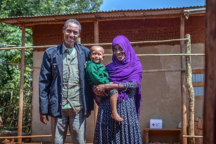 Paar mit Kind vor Haus und Hilfspaket