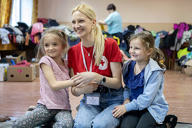 Rotkreuz-Freiwillige lacht mit zwei Mädchen