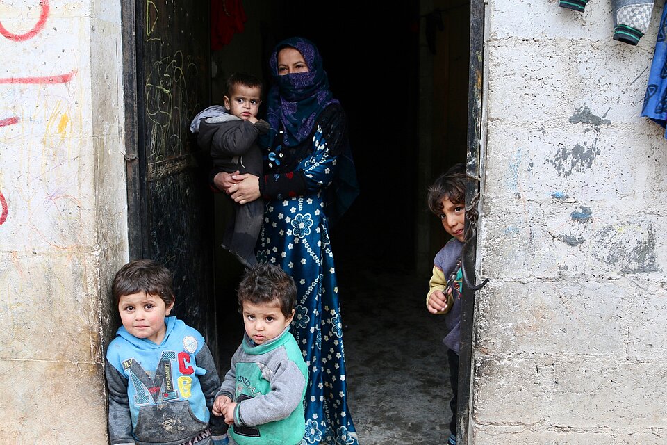 Eine verschleierte Frau steht mit ihren Kindern in einer Tür