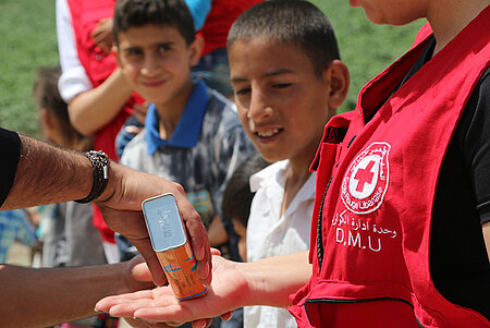 Foto: Ein Helfer gibt Flüssigseife auf die Hand einer Helferin beim Kindertraining
