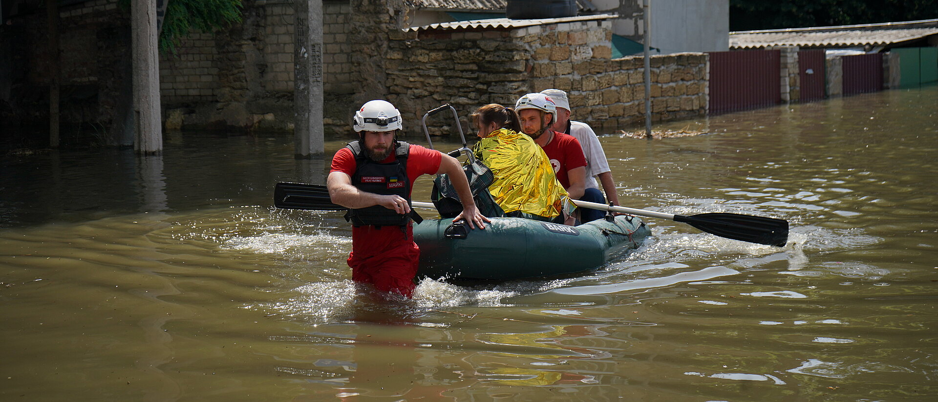 Helferinnen und Helfer des Ukrainischen Roten Kreuzes ziehen ein Boot durch das Hochwasser.