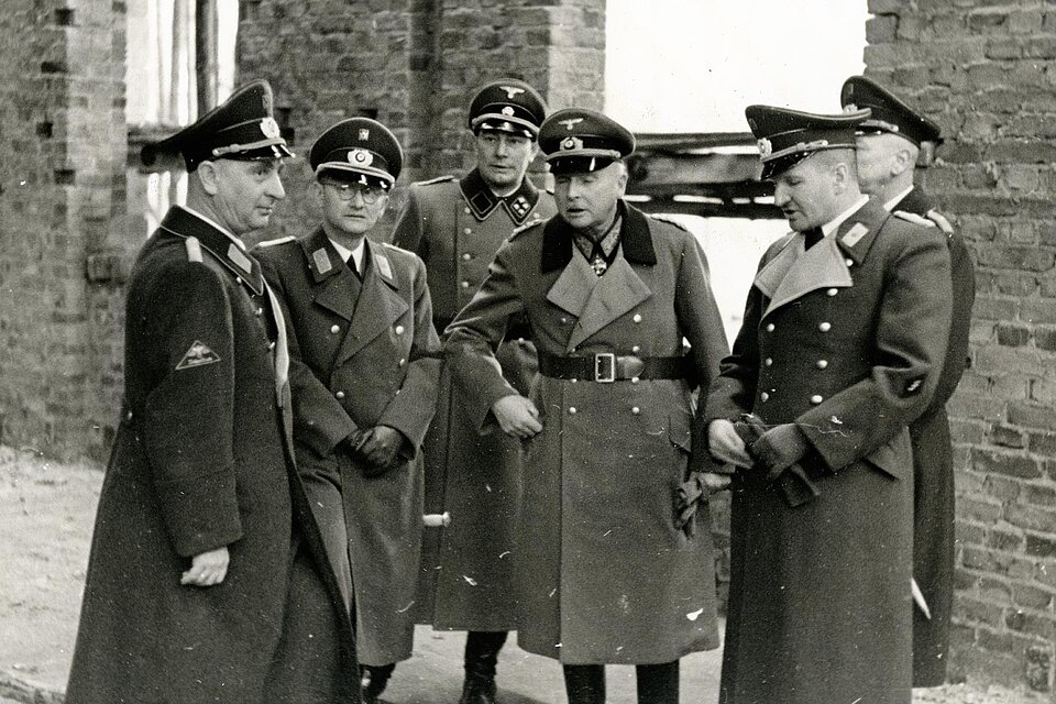 Gruppe uniformierter Männer vor Rohbau