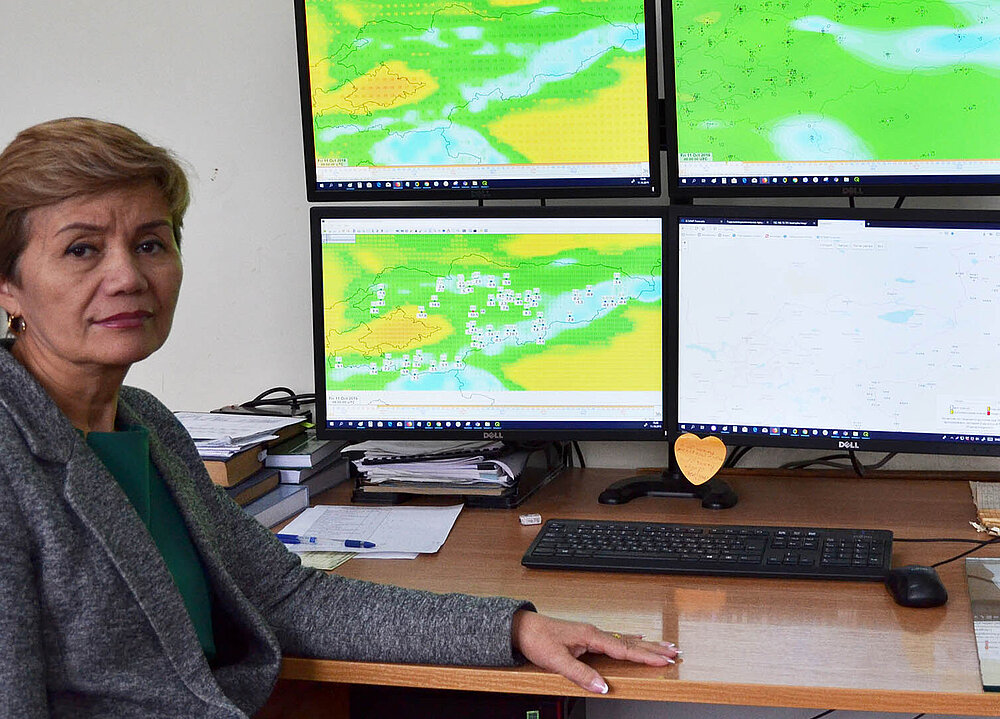 Frau am Schreibtisch mit vier Bildschirmen