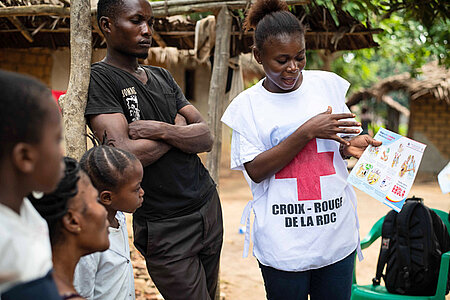 Foto: Eine Rotkreuz-Helferin informiert eine Familie über Ebola