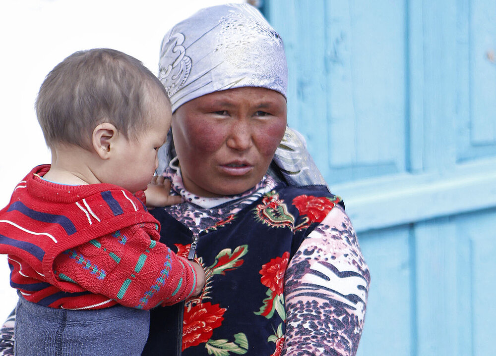 Kirgisische Mutter mit Kind auf dem Arm