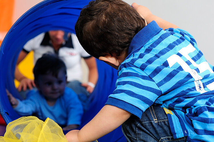 Zwei Kinder spielen mit Stofftunnel