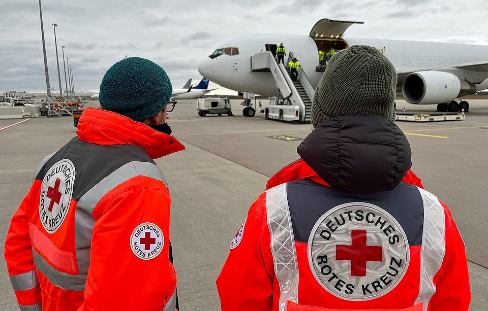 Zwei DRK-Mitarbeitende vor dem Flugzeug, das Hilfsgüter für den Gaza-Streifen transportiert