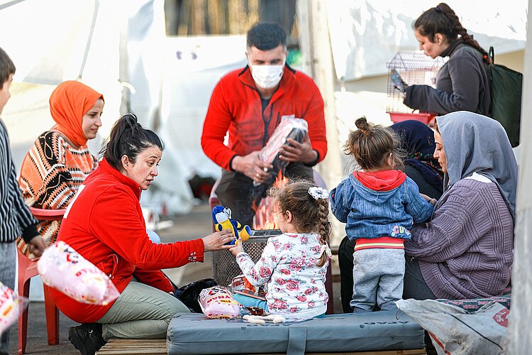 Kinder spielen mit Helferinnen und Helfer des Türkischen Roten Halbmonds und erhalten Spielzeug.