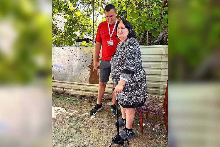 Rotkreuzler und Seniorin mit Krücke