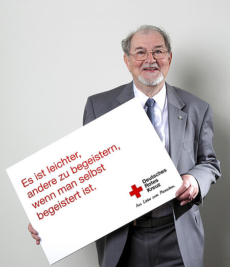 Christoph Brückner hält Schild mit Slogan einer DRK-Kampagne