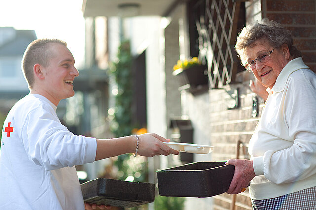 DRKler übergibt Box an Seniorin
