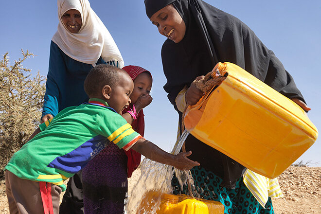 somalische Kinder freuen sich über Wasser aus Kanister