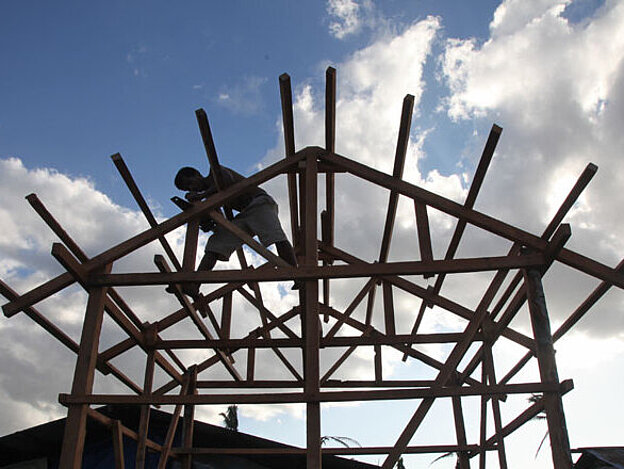 Foto: Handwerker auf dem Holzgerüst eines Daches