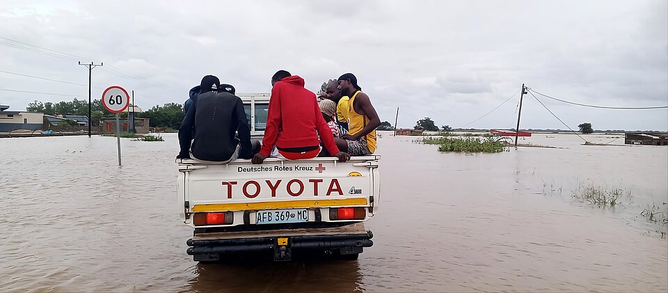 Hilfe während der Überflutungen in Mosambik Menschen auf der Ladefläche eines DRK-Pickups fahren durch eine überflutete Landschaft