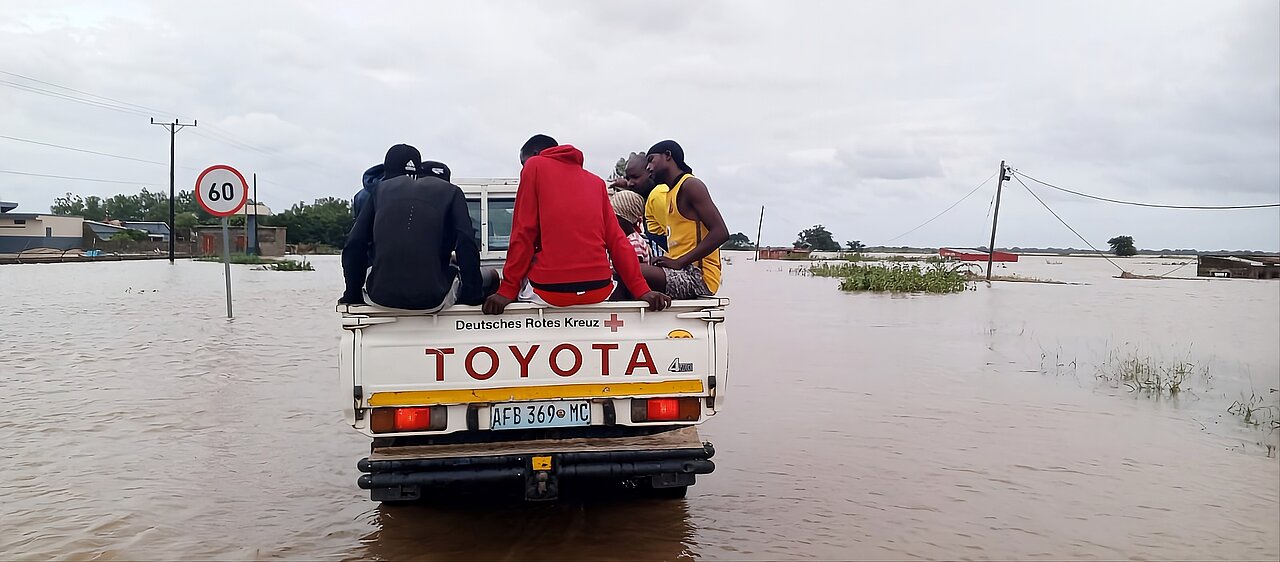 Hilfe während der Überflutungen in Mosambik Menschen auf der Ladefläche eines DRK-Pickups fahren durch eine überflutete Landschaft