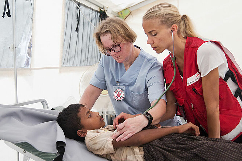 Zwei medizinische Helferinnen des Finnischen Roten Kreuzes untersuchen einen Jungen aus Rakhine im mobilen Krankenhaus