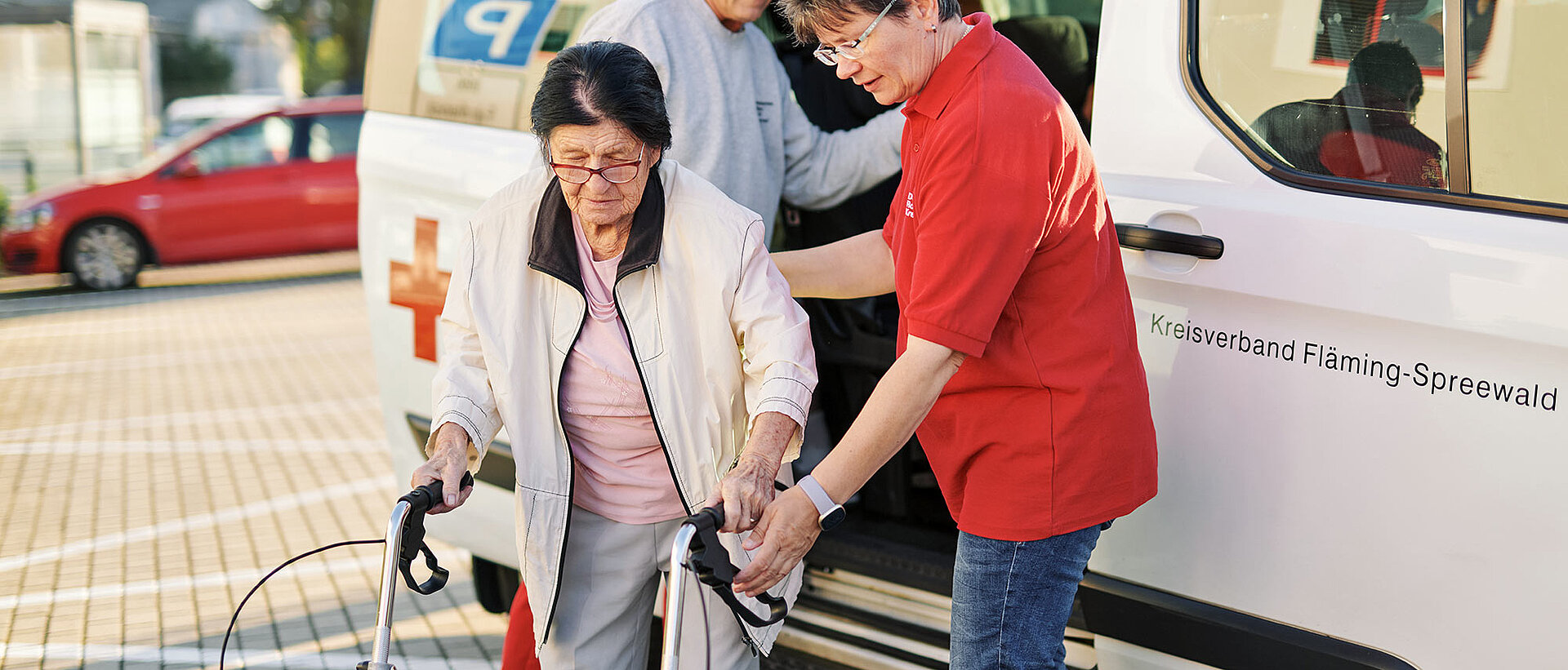 Seniorin steigt aus DRK-Fahrdienst-Fahrzeug aus