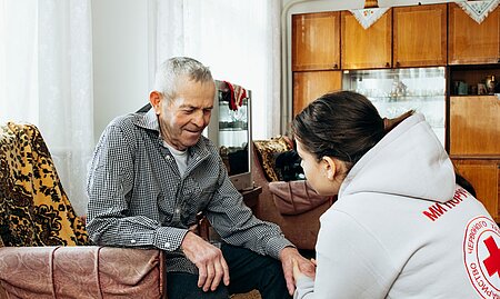 Frau hält älterem Mann die Hand und wendet sich ihm zu.
