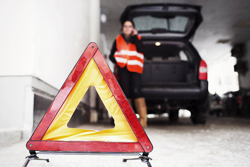 Warndreieck vor Auto mit telefonierender Frau