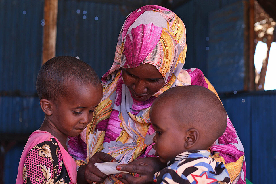Somalierin in buntem Kopftuch mit 2 Kleinkindern