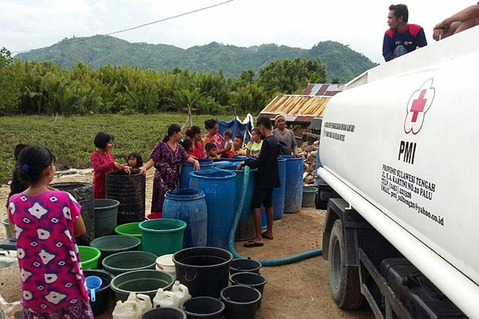 Mitarbeiter des Indonesischen Roten Kreuzes helfen der Bevölkerung mit Wasser