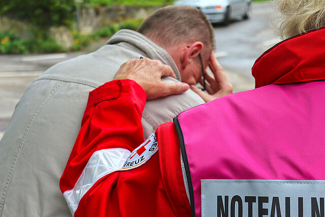 Frau legt Arm auf Schulter eines weinenden Mannes