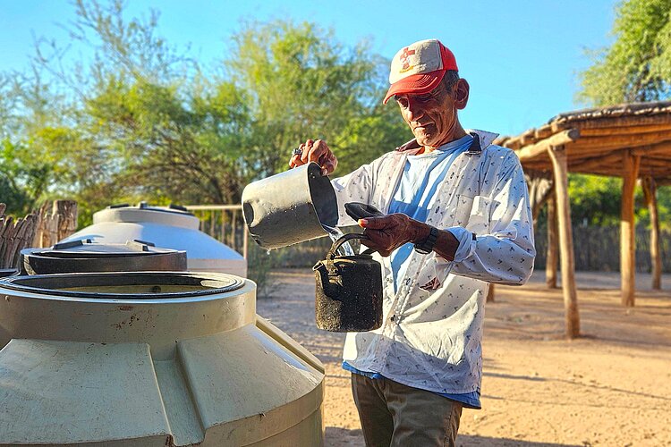 Mann schöpft Wasser aus Container