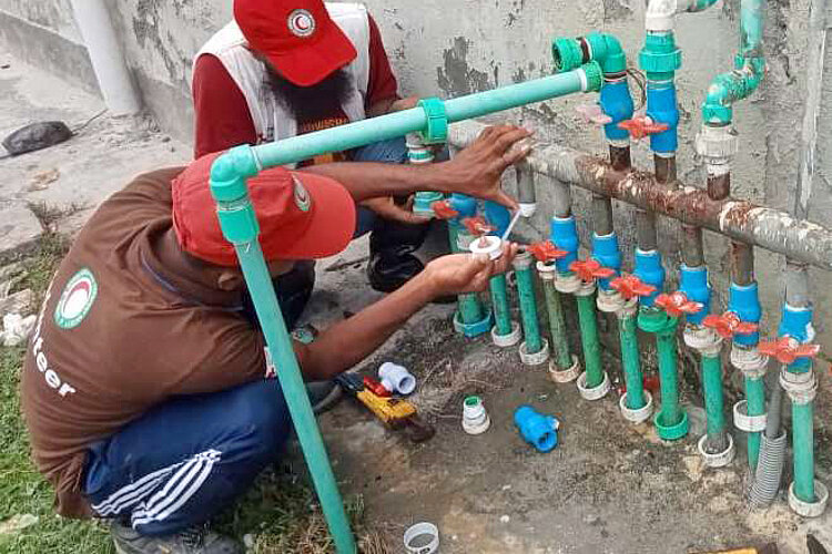 Zwei Helfer bei Arbeit an Wasserrohren