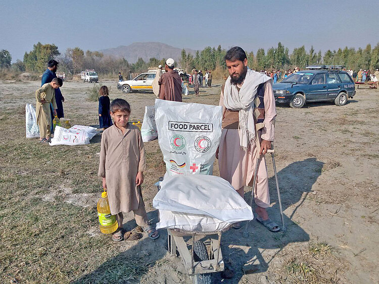 Junge und Mann mit Lebensmittel-Paket in Afghanistan