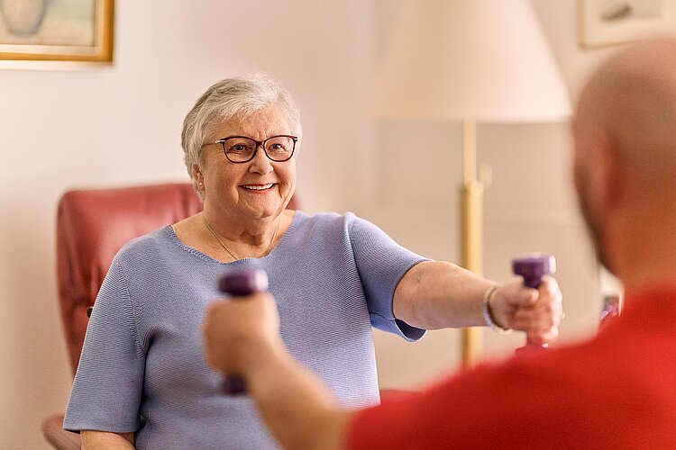 Seniorin und DRKler bei Gymnastik mit Hanteln