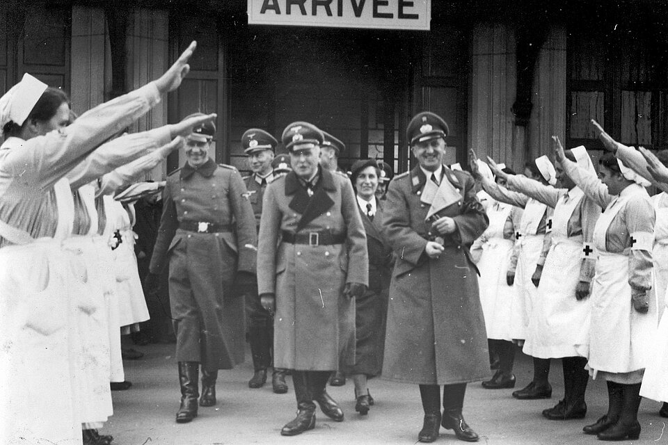 DRK-Helferinnnen begrüßen Männer mit Hitlergruß