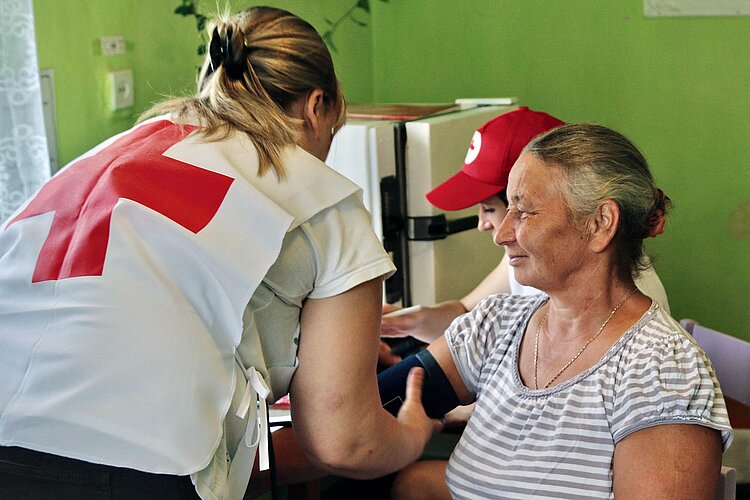 Ukraine-Hilfe Rotkreuzlerin misst Blutdruck bei Seniorin