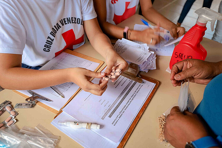 Rotkreuzlerin händigt Tabletten aus