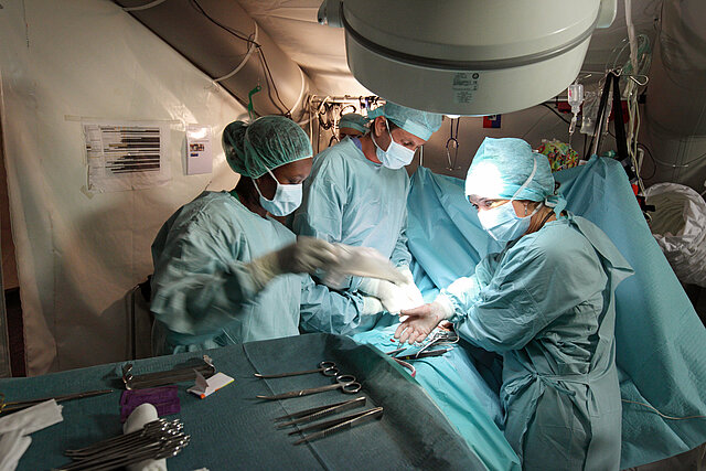 Medizinisches Personal in OP-Kleidung operiert in einem Zelt in Haiti