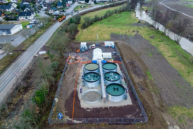 Luftaufnahme der Kläranlage durch eine Drohne. Es werden die Tanks und der Gerüstaufbau gezeigt. Im Hintergrund sieht man den Fluss Ahr und das Dorf Hönningen.