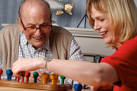 Ein alter Mann und eine mittelalte Frau spielen zusammen ein Brettspiel