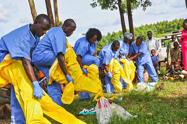 Ugandische Helfende ziehen sich Schutzanzüge an