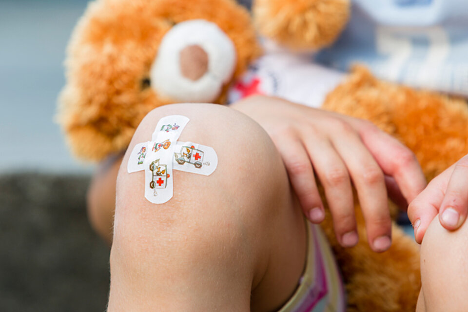 Kinderknie mit Pflaster und Teddy