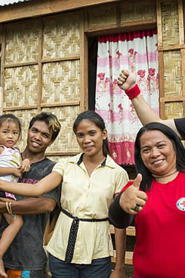 Foto: Philippinische Familie mit Helfern vor einem neuen Bambushaus