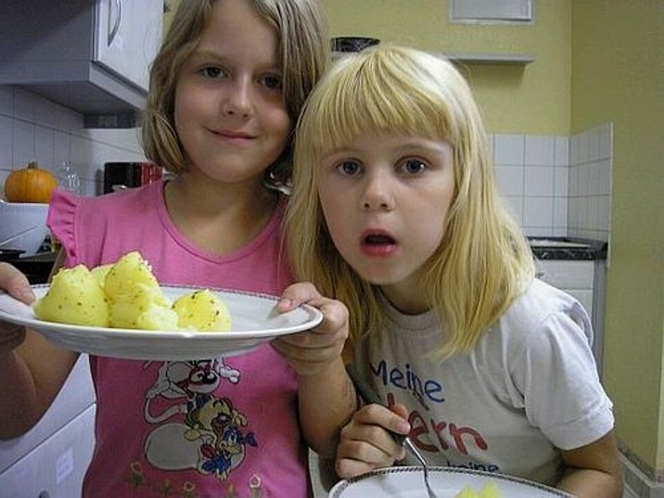 Foto: Zwei Mädchen präsentieren einen Teller selbstgekochtes Essen