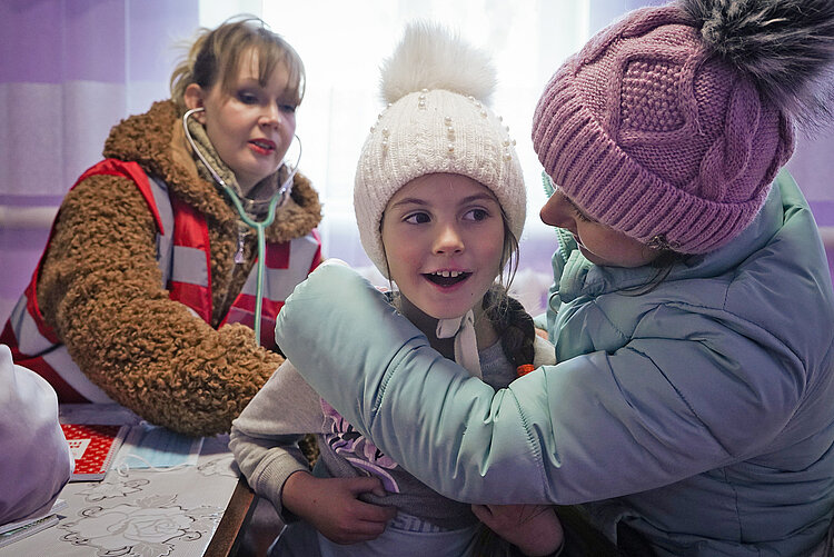 Rotkreuz-Helferin, Kind und Frau in mobiler Gesundheitsstation in der Ukraine